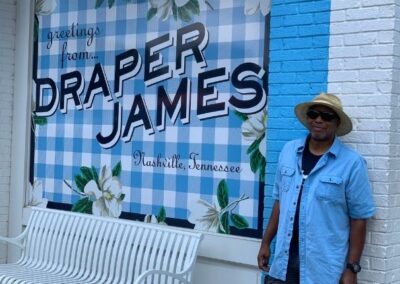man standing next to the Draper James mural in Nashville