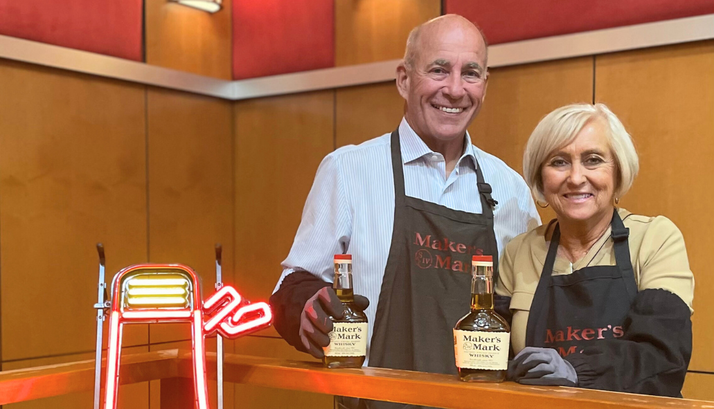 Older couple posing with bottles of Makers Mark whiskey