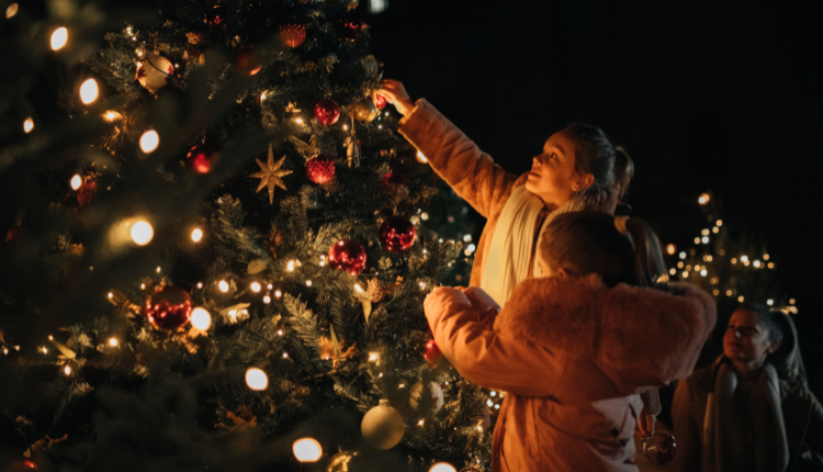 Two girls hanging lights on Christmas Tree