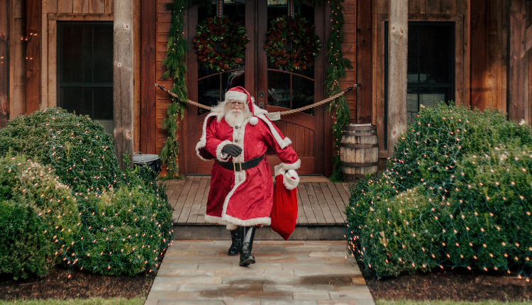 Santa Claus with gift bad walking out of festive house